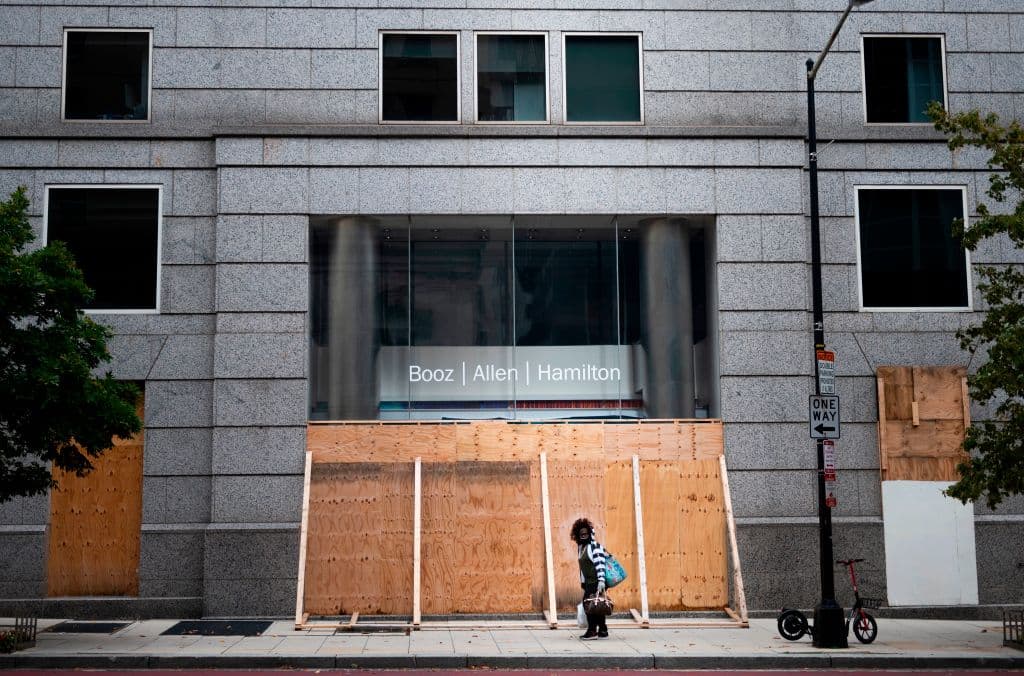 A woman walks past a Booz Allen Hamilton office three days before the 2020 presidential election, in Washington, D.C. (Photo by ANDREW CABALLERO-REYNOLDS—AFP/Getty Images)