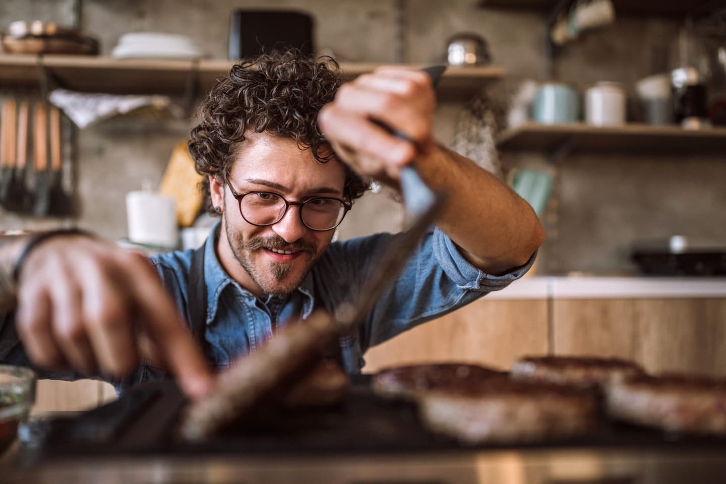 Hipster man turns a burger on a grill