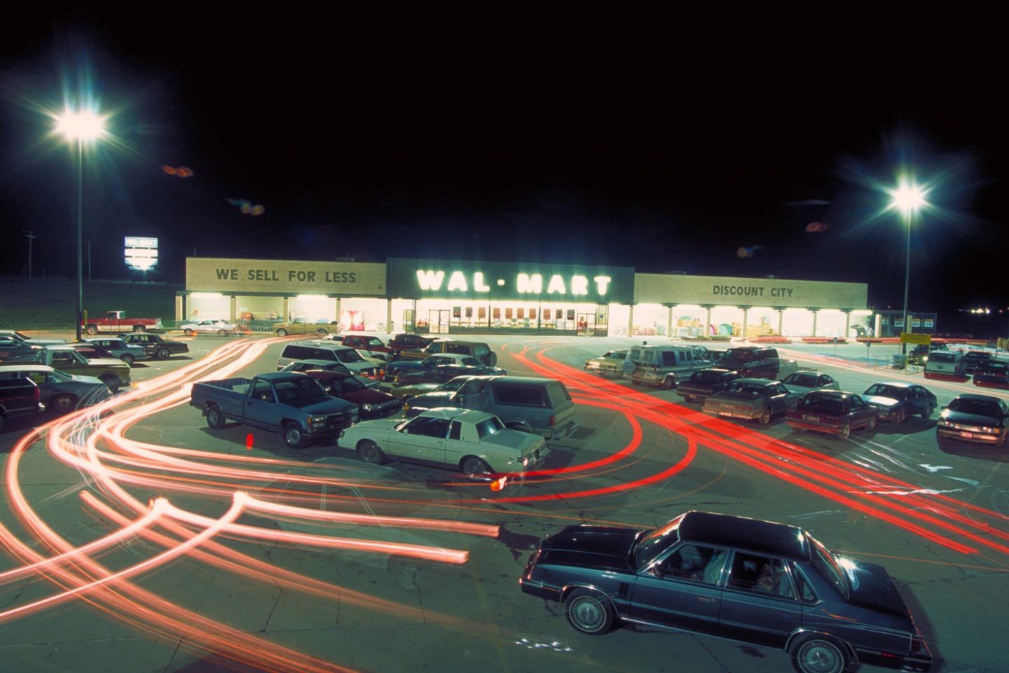 A time exposure photograph of a parking lot at night outside of a Walmart store.