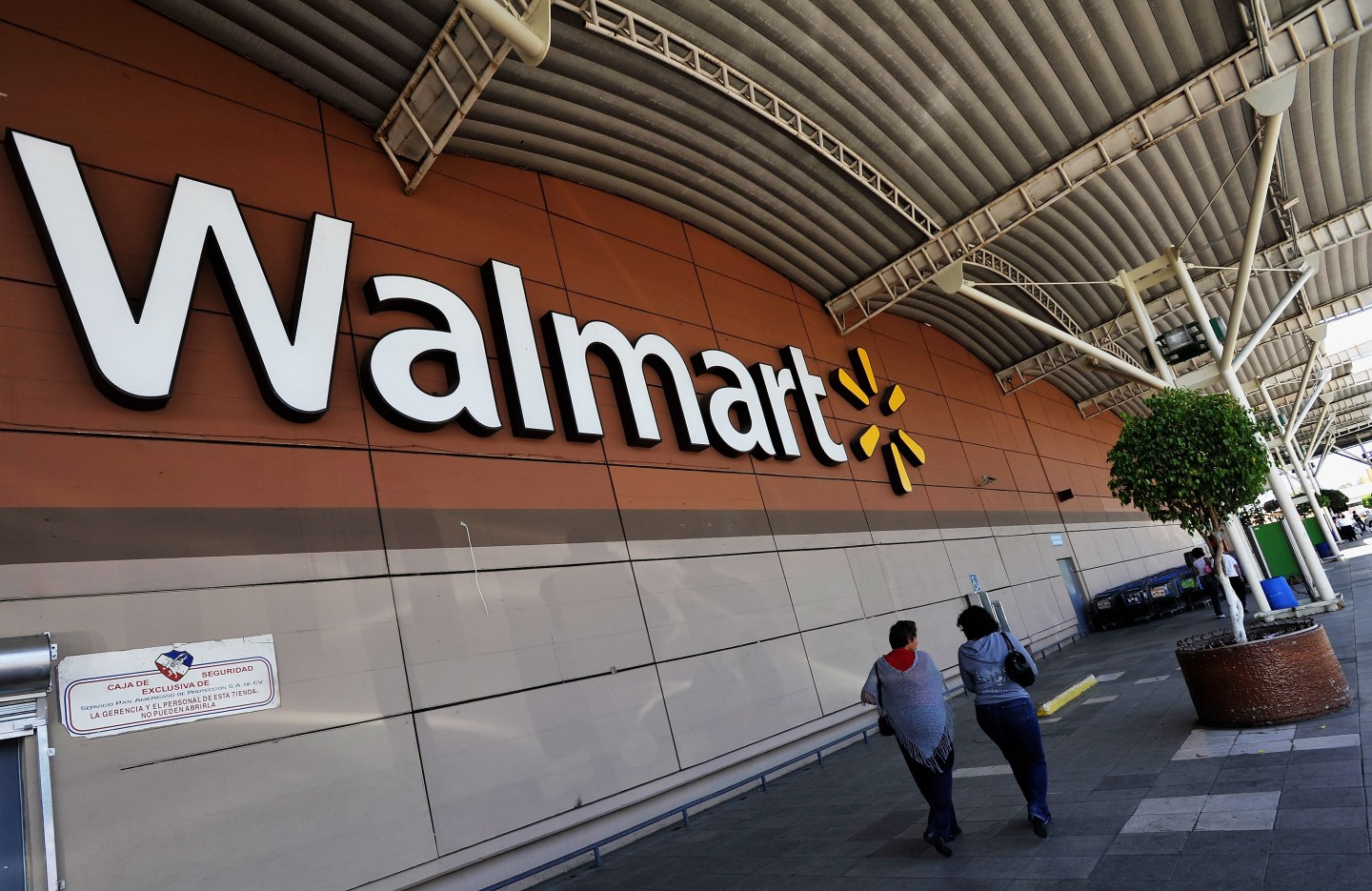MEXICO CITY, MEXICO - APRIL 23:  People walk through the lot past Wal-Mart store signage on April 23, 2012 in Mexico City, Mexico. According to reports, Wal-Mart de Mexico orchestrated a campaign of bribery to win market dominance by paying bribes to obtain permits in parts of the country. Wal-Mart Inc, along with two U.S. congressmen is conducting internal investigations over the allegations.  (Photo by Daniel Aguilar/Getty Images)