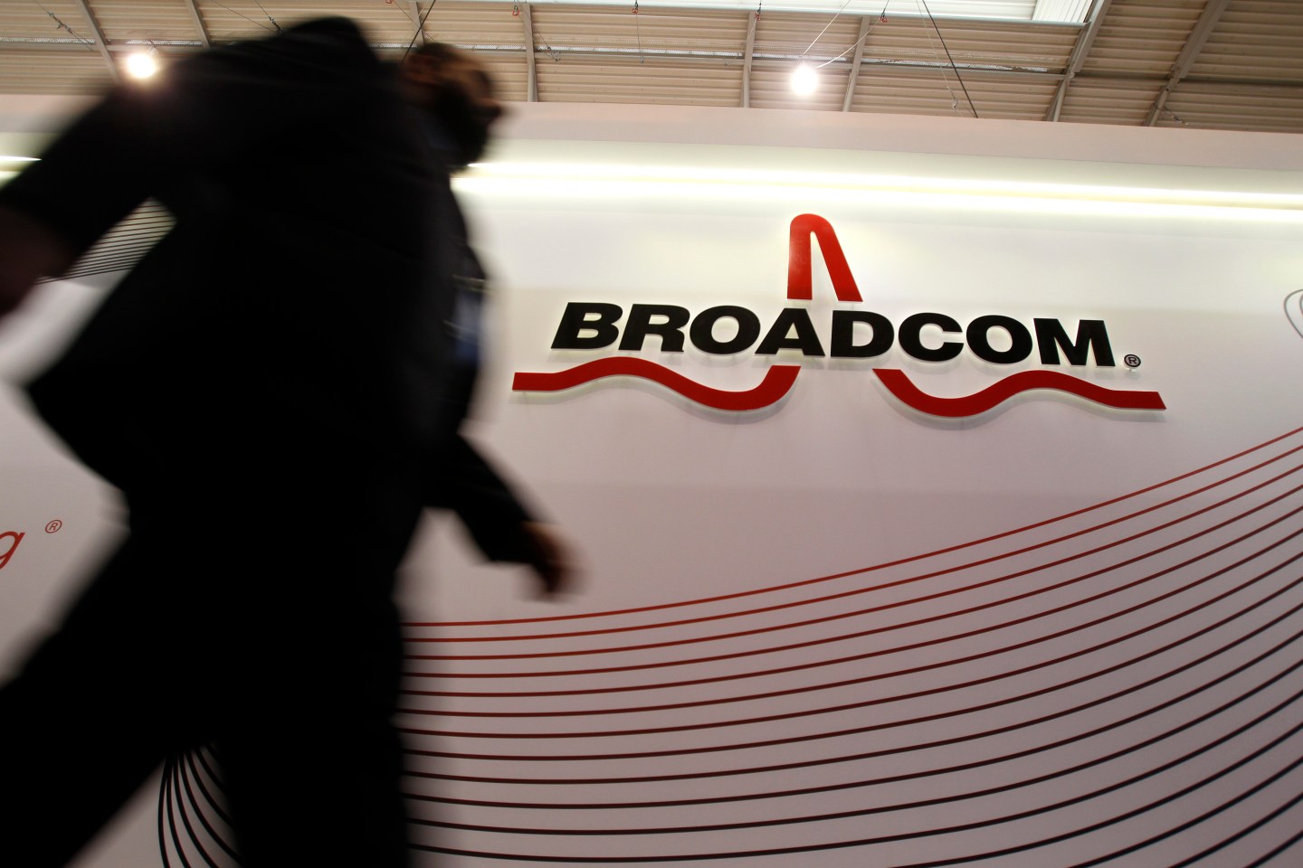 An attendee passes the Broadcom Corp. pavilon on day two of the Mobile World Congress in Barcelona, Spain, on Tuesday, Feb. 25, 2014. Top telecommunication managers will rub shoulders in Barcelona this week at the Mobile World Congress, Monday, Feb. 24 - 27, a traditional venue for showcasing the latest products for dealmaking. Photographer: Angel Navarette/Bloomberg