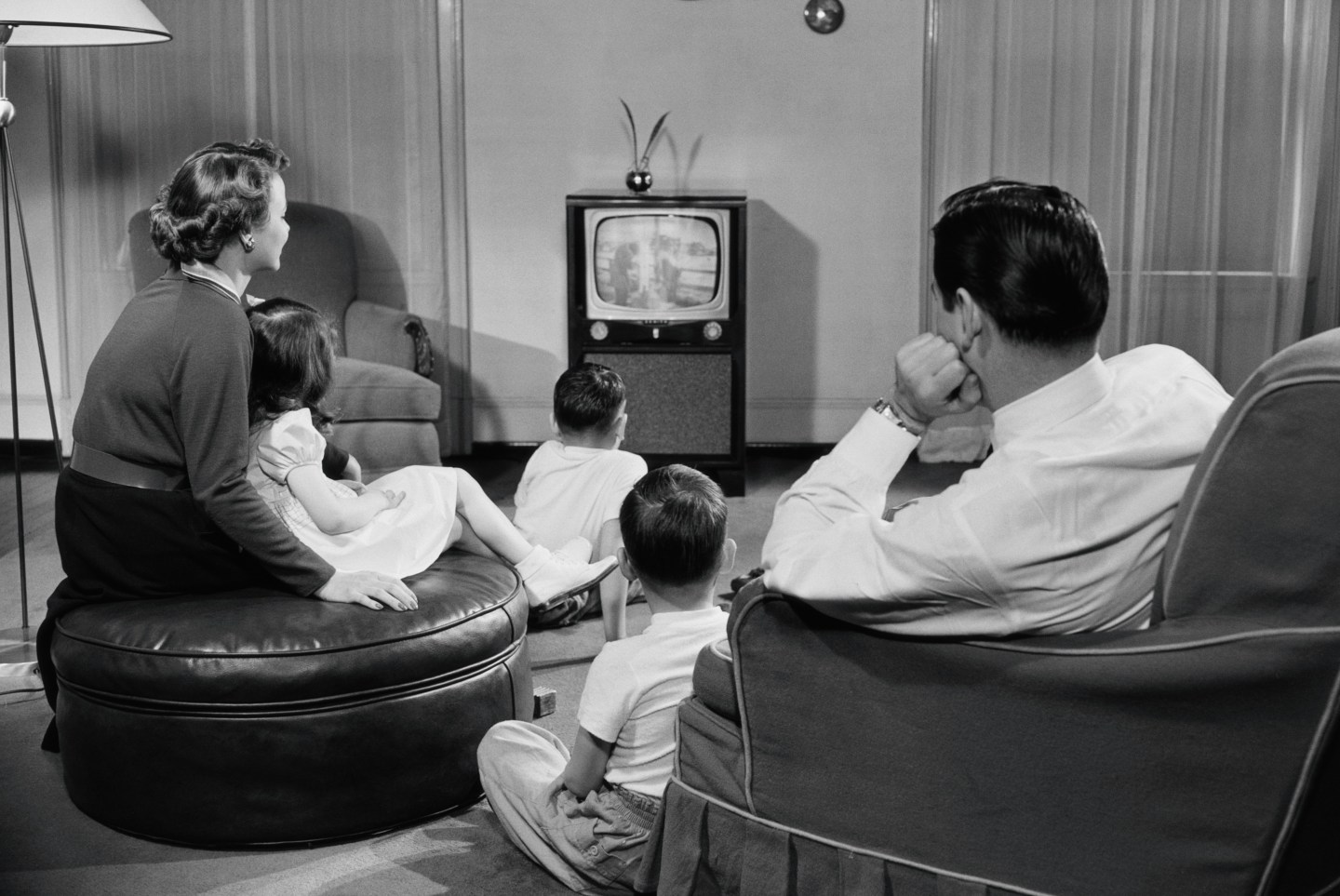 A family watches TV in the living room in the 1950s.