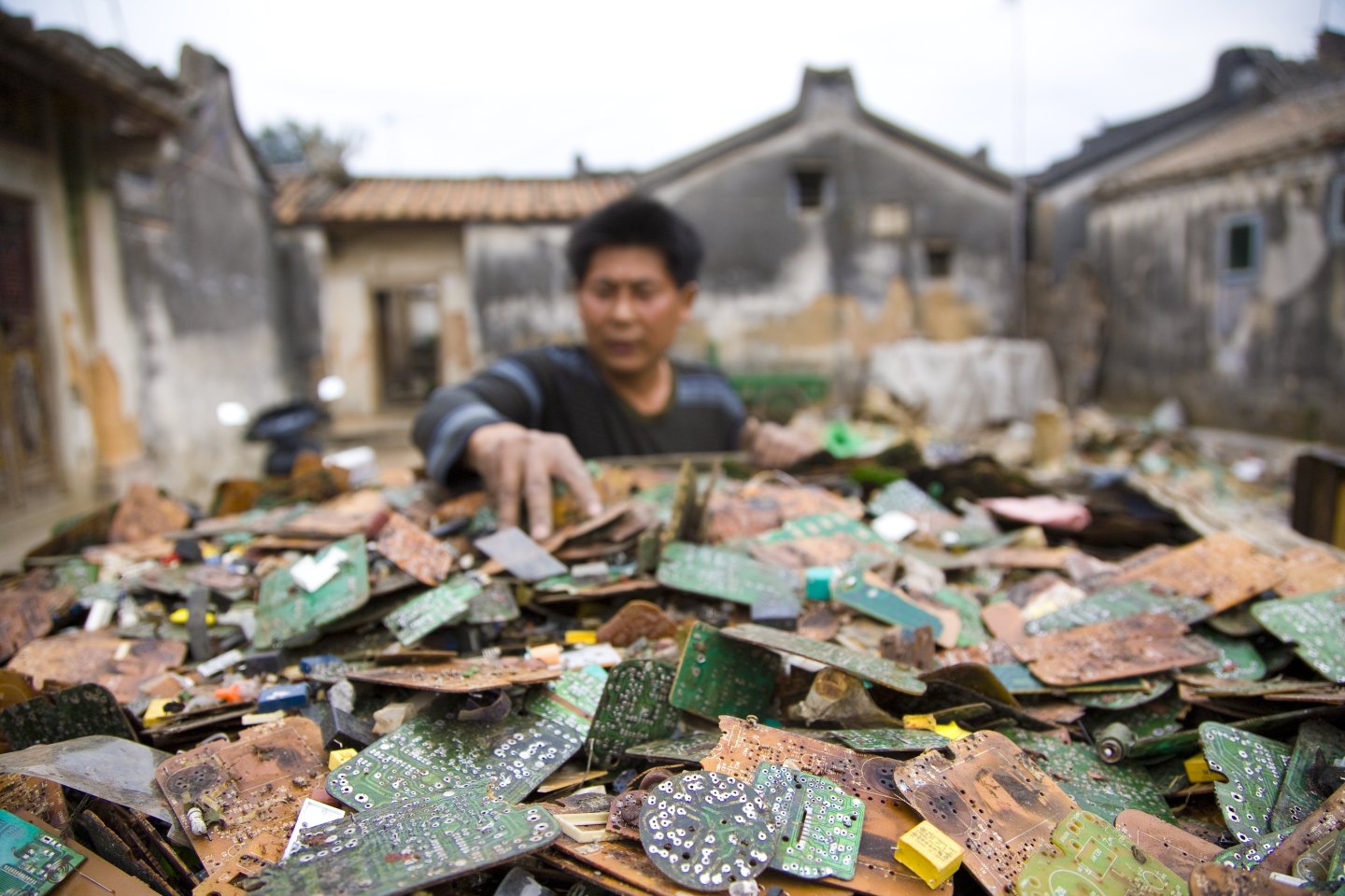 A worker sorts through stripped computer boards in Guiyu, China in 2008.