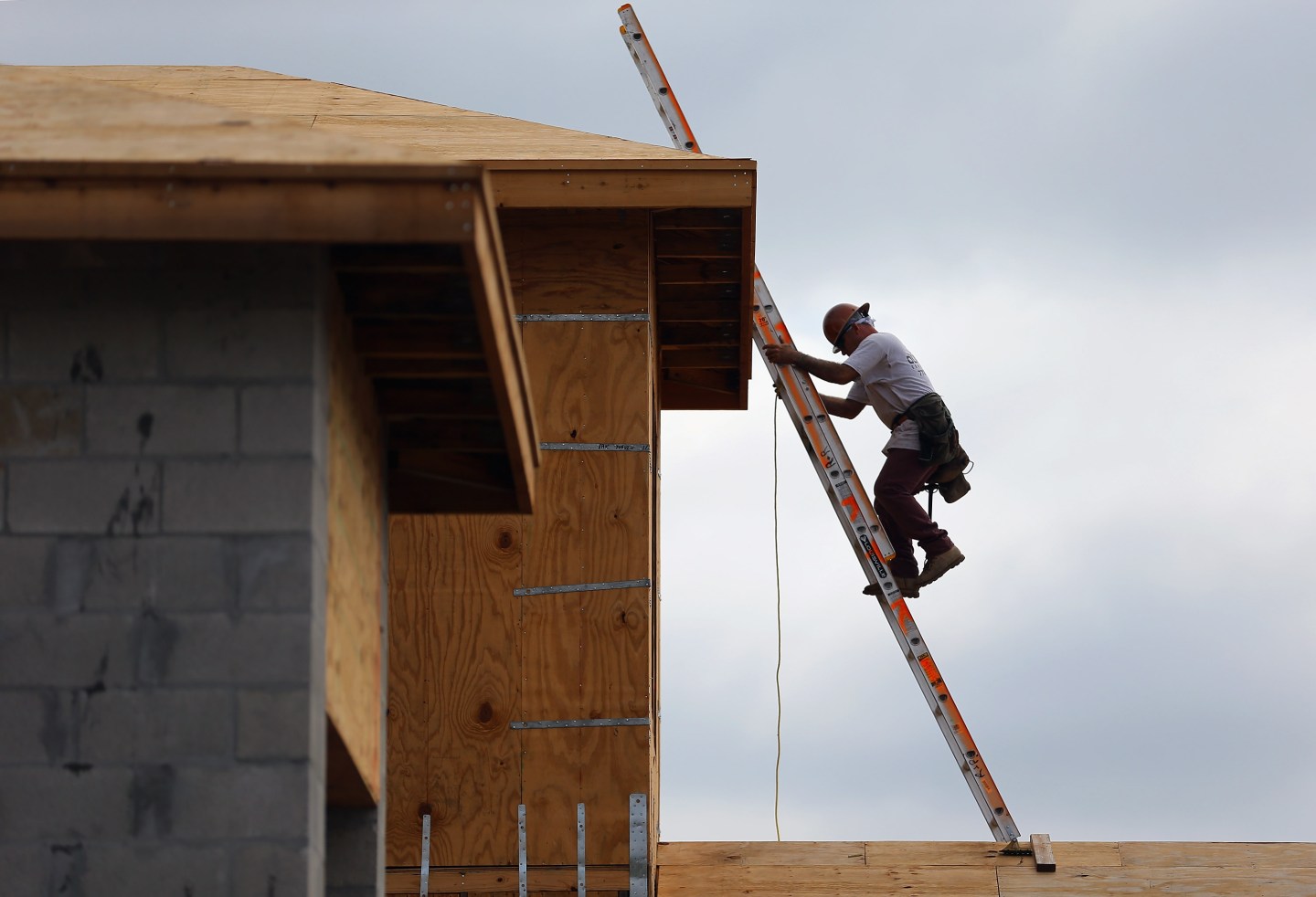 A construction worker climbs on the roof of a home as he helps build a Toll Brothers Inc. home.