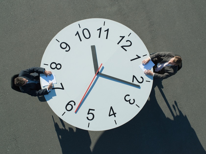 Two businessmen sitting at a clock table