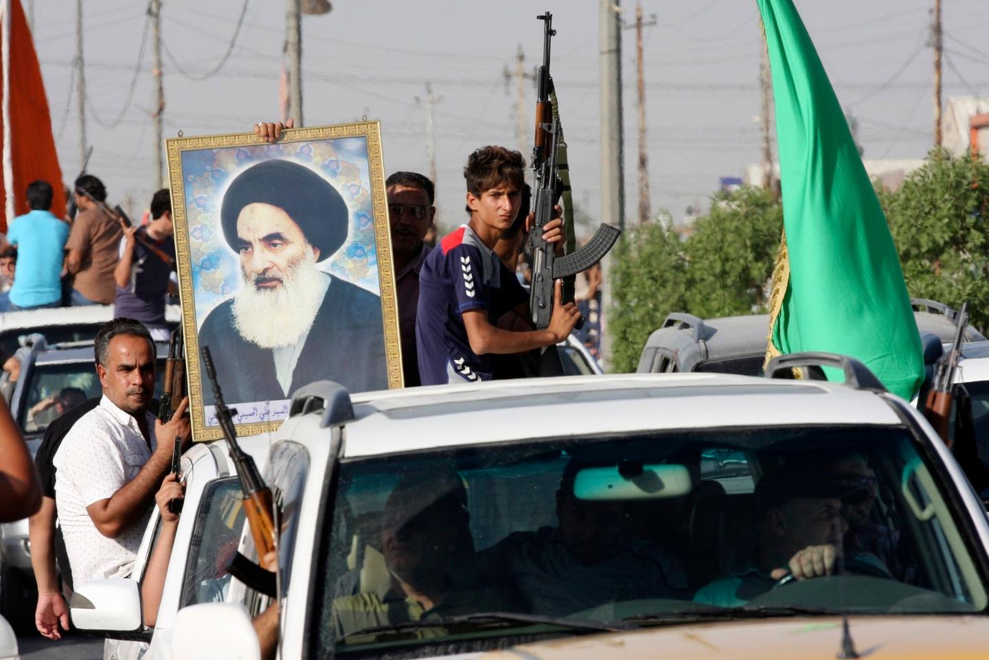 Volunteers, who have joined the Iraqi Army to fight against predominantly Sunni militants, carry weapons and a portrait of Grand Ayatollah Ali al-Sistani during a parade in Sadr city
