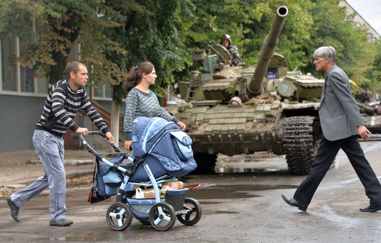 Local residents pushing a pram walk past an Ukrainian tank in the eastern Ukrainian city of Slavyansk on July 8, 2014.
