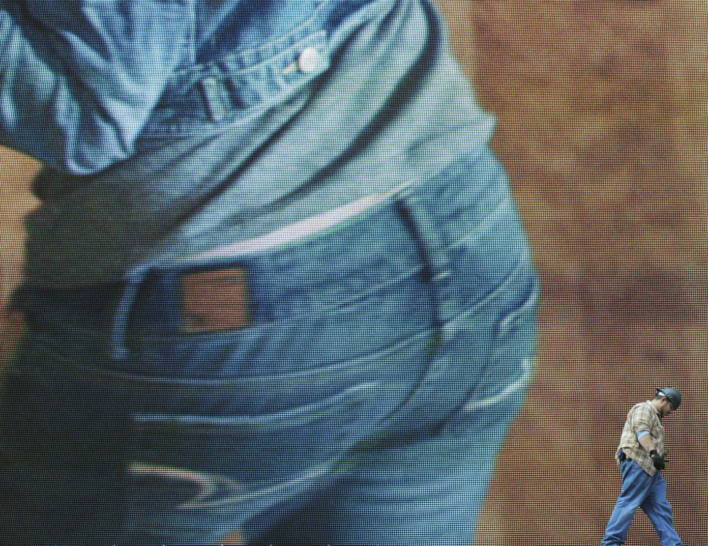 A billboard worker walks past a giant sc