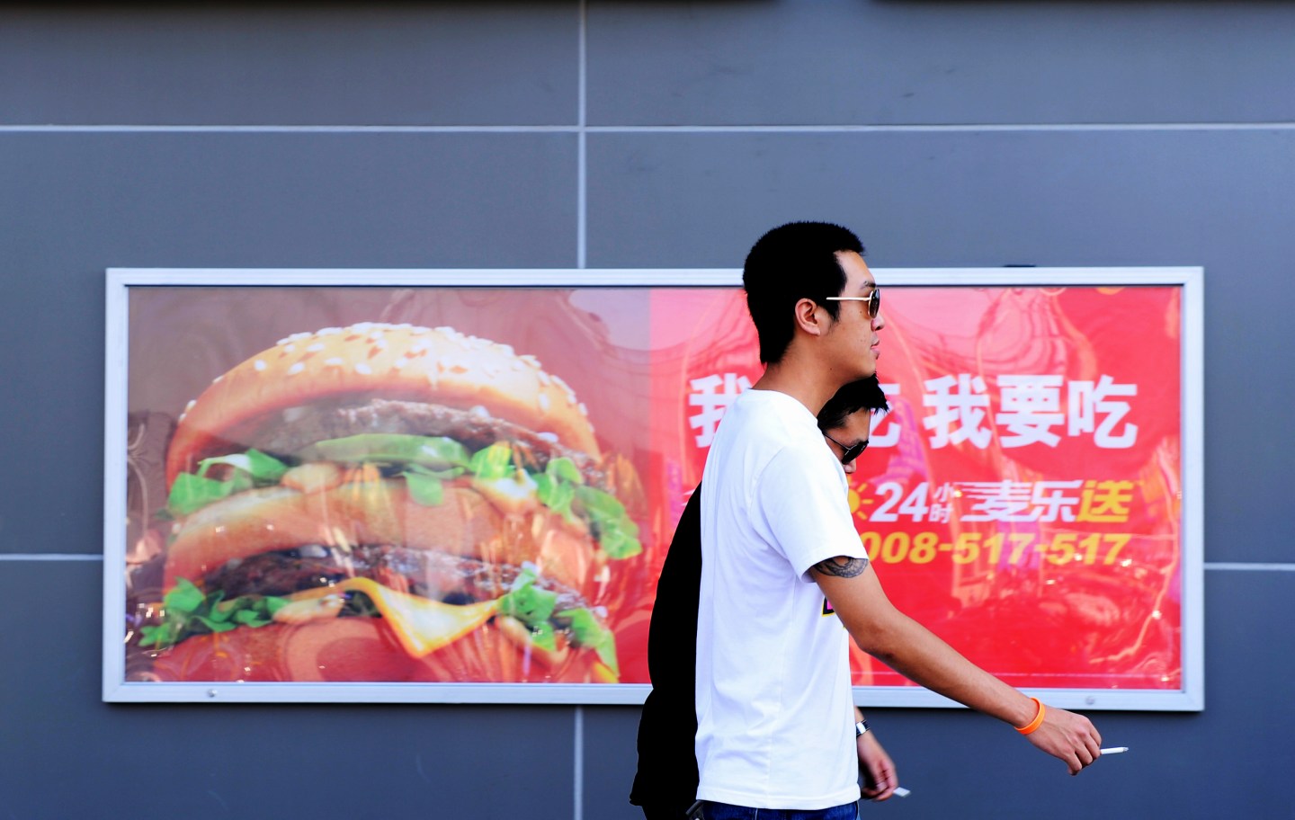 Two Chinese men walk past a billboard ad
