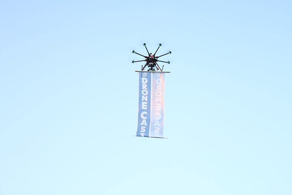 A DJI S1000 octocopter carrying a vertical banner during a DroneCast promotional flight in Philadelphia.