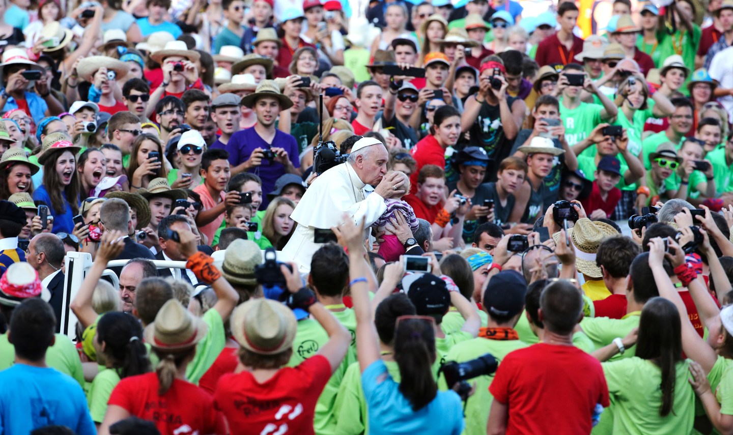 Pope Francis kisses a child as he arrives to leads a meeting with altar workers in St Peter's square at the Vatican