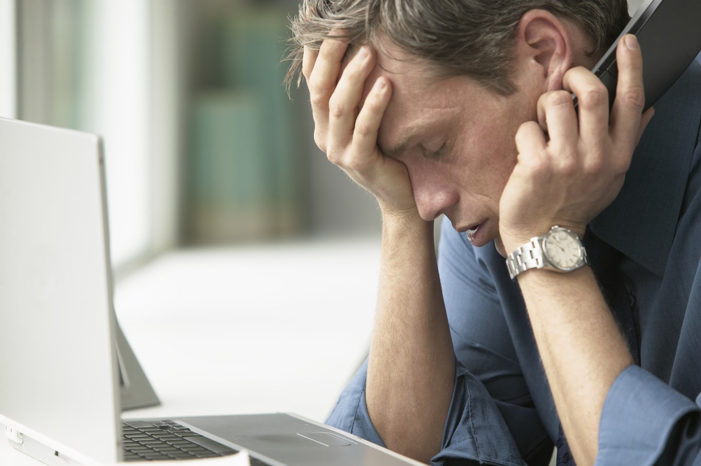 Exhausted Businessman with Laptop and Cell Phone