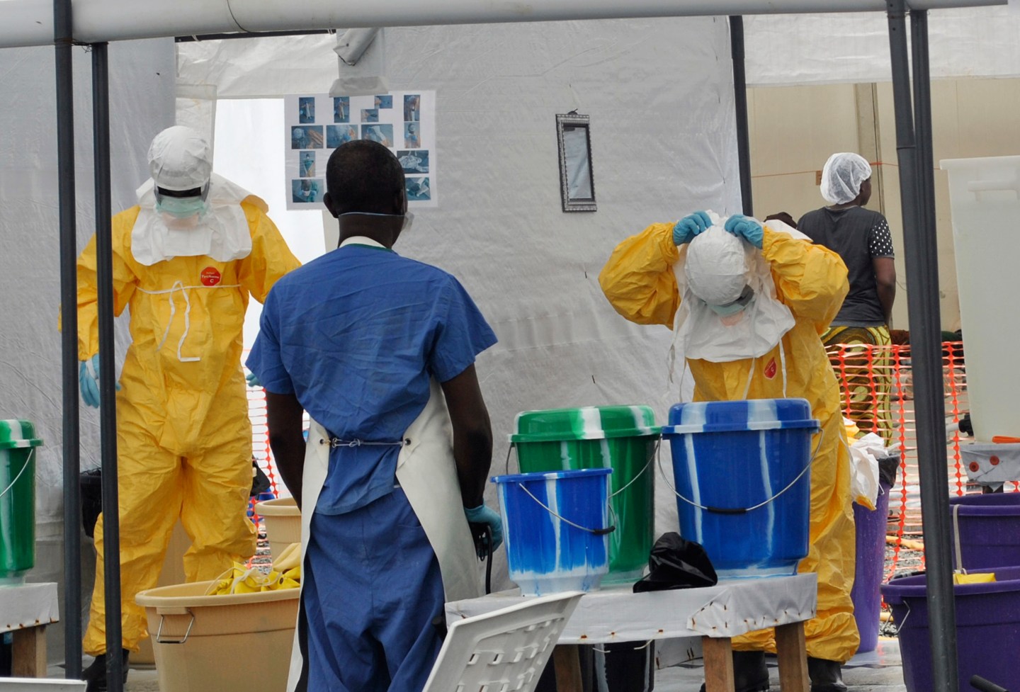 A Doctors Without Borders health worker takes off his protective gear under the surveillance of a colleague at a treatment facility for Ebola victims in Monrovia