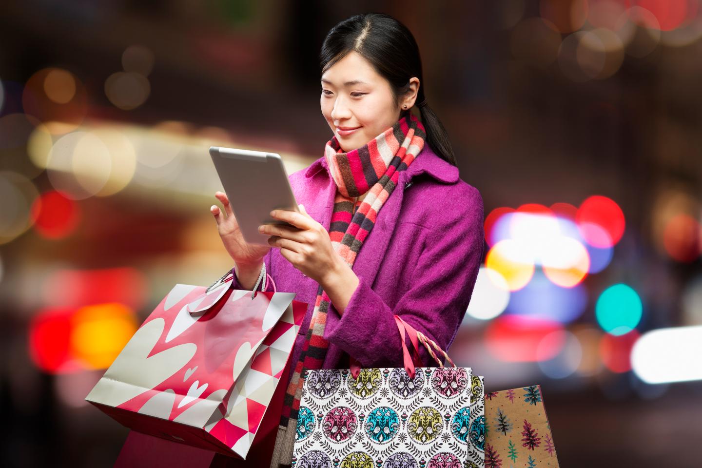 Woman checking wireless device in city,
