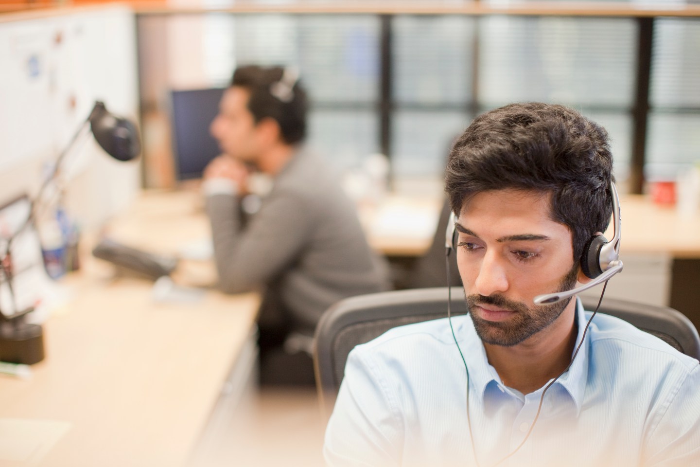 Indian businessman wearing headset at desk