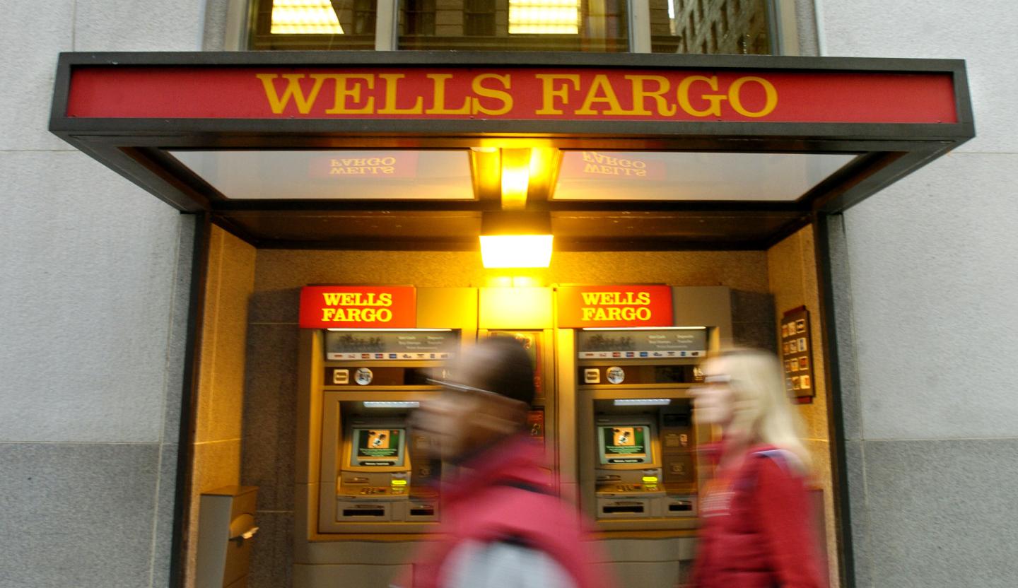 Pedestrians pass an ATM outside Wells Fargo & Co.'s San Fran