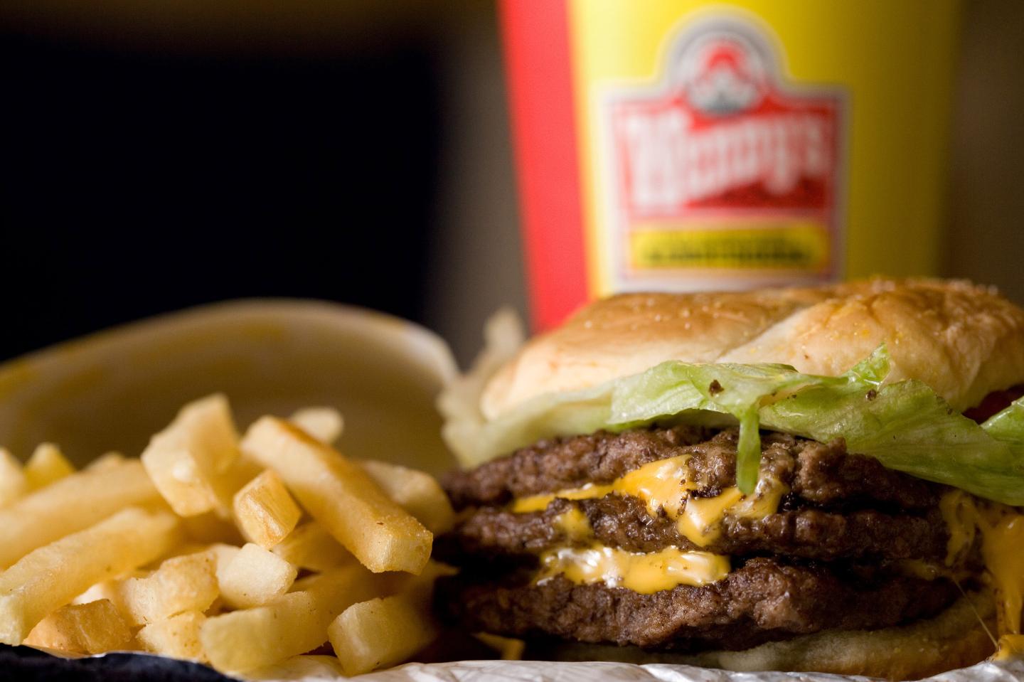 A triple cheeseburger combo is arranged for a photograph in