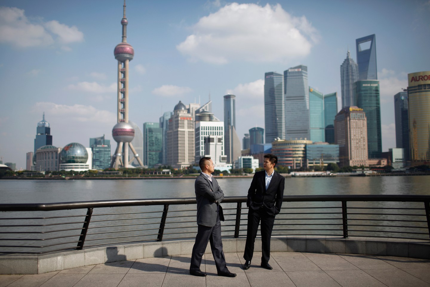 Businessmen walk on the Bund near the Huangpu River in front of the financial district of Pudong in Shanghai