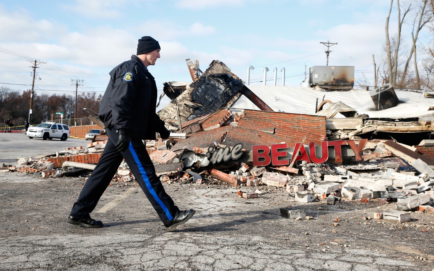 A police officer looks over the site of a building that was burned in riots the previous night in Ferguson