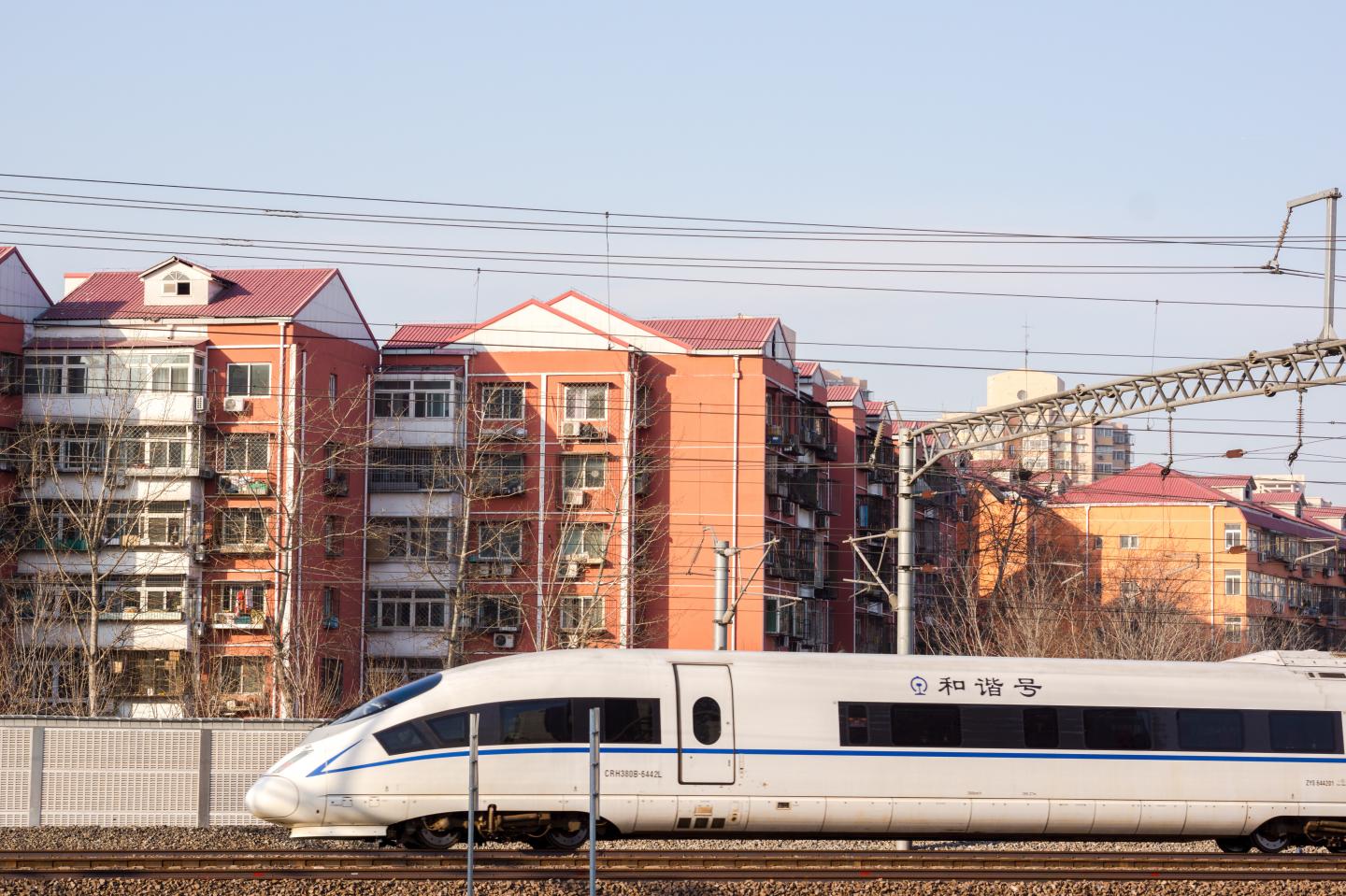 A high speed train is driving past a residential district.