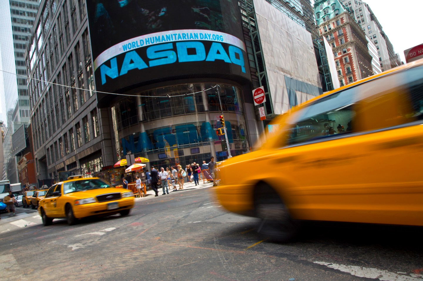 Taxi cabs drive past the Nasdaq MarketSite in New York's Times Square