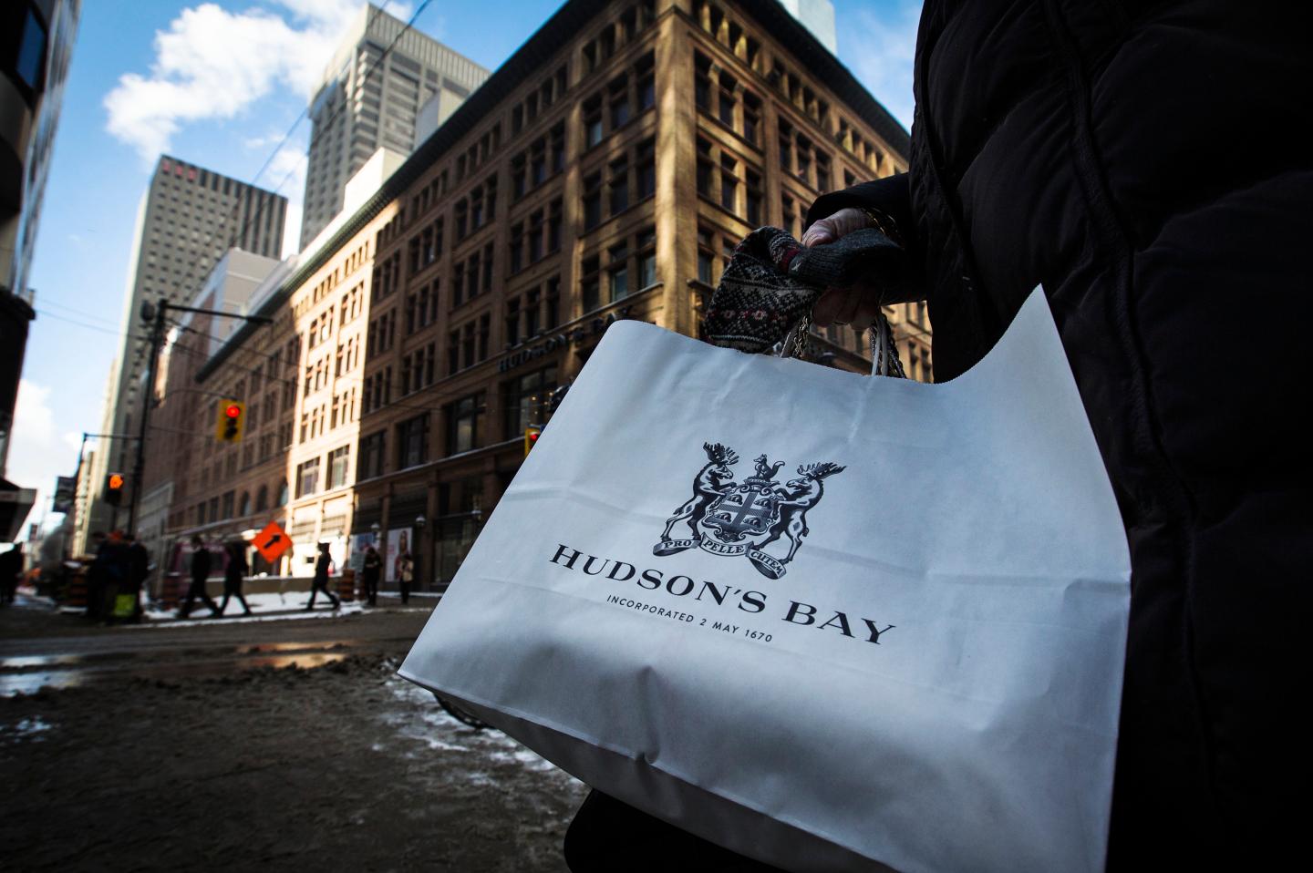 A woman holds a Hudson's Bay shopping bag in front of the Hudson's Bay Company (HBC) flagship department store in Toronto