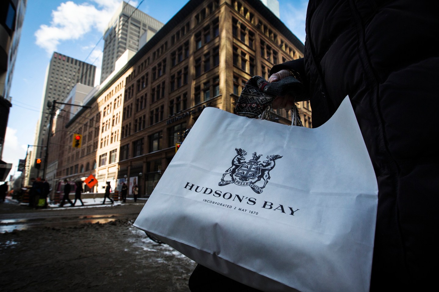 A woman holds a Hudson's Bay shopping bag in front of the Hudson's Bay Company (HBC) flagship department store in Toronto