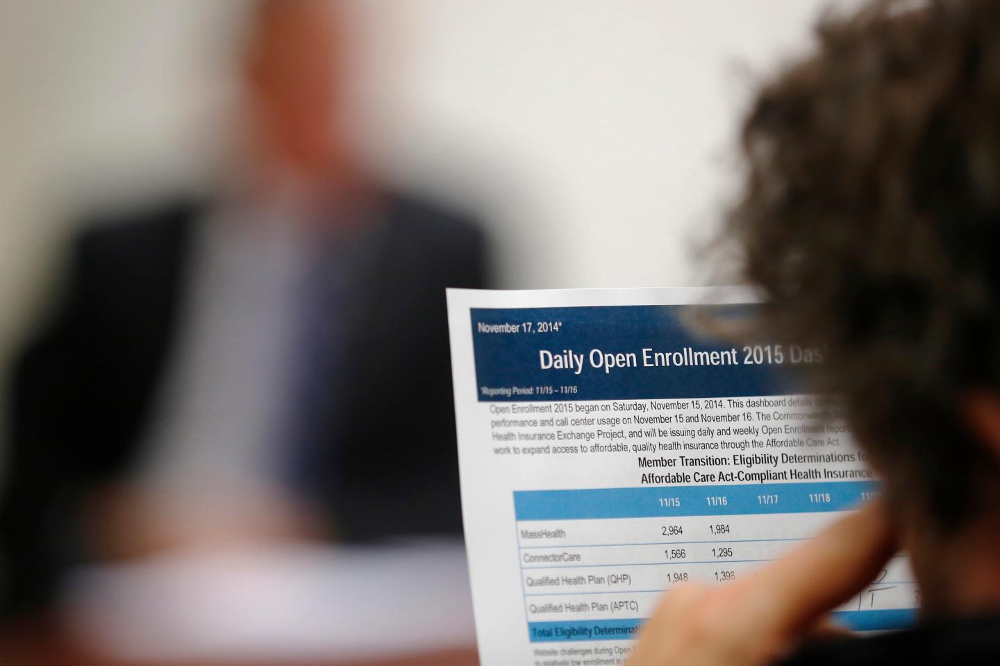 A reporter reads a summary of the performance and usage of the Massachusetts Health Connector website during a briefing for reporters in Boston