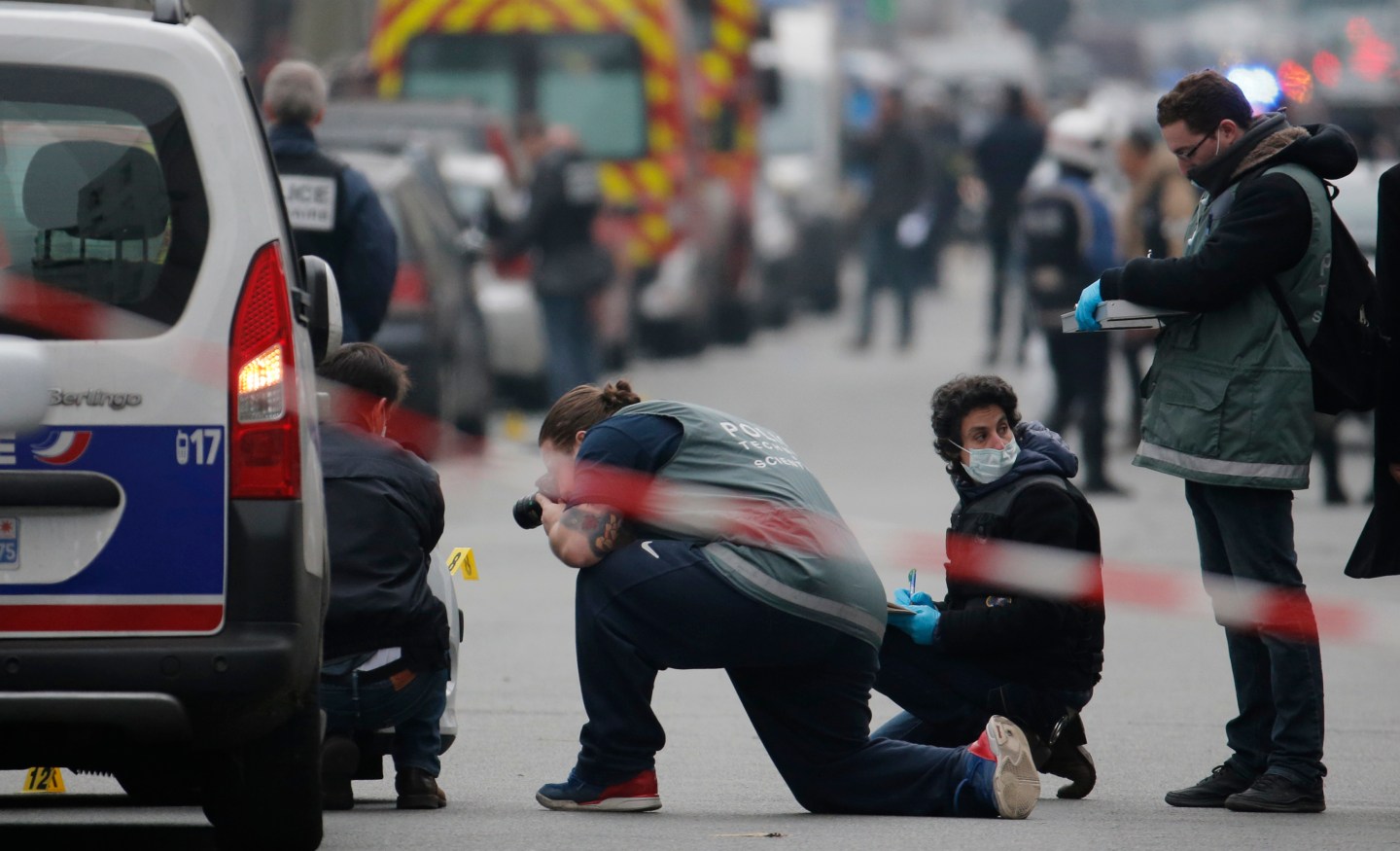 Police investigators examine the impacts from machine gun fire on the front of a police vehicle in the street near the Paris offices of Charlie Hebdo