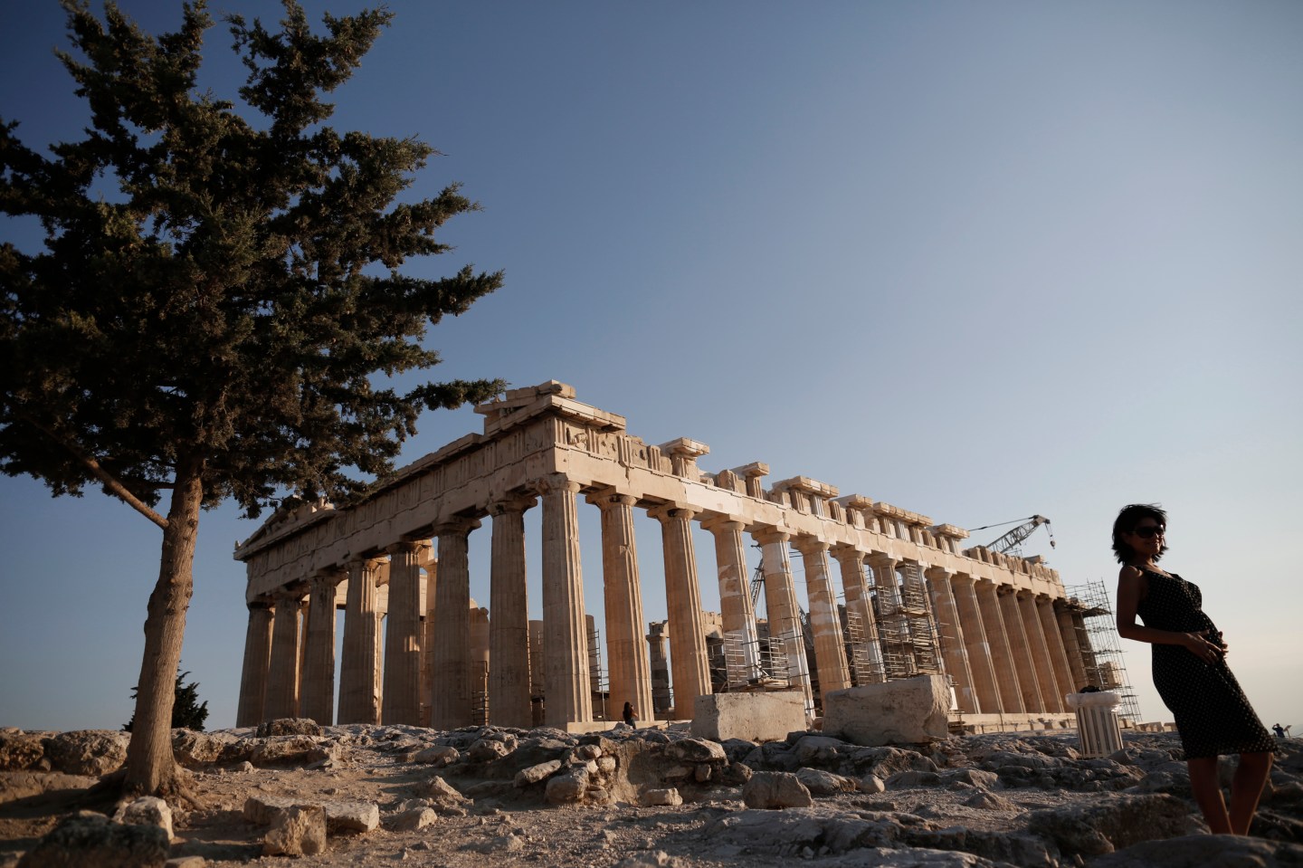 A tourist stands in front of the temple of the Parthenon at the the Acropolis hill in Athens