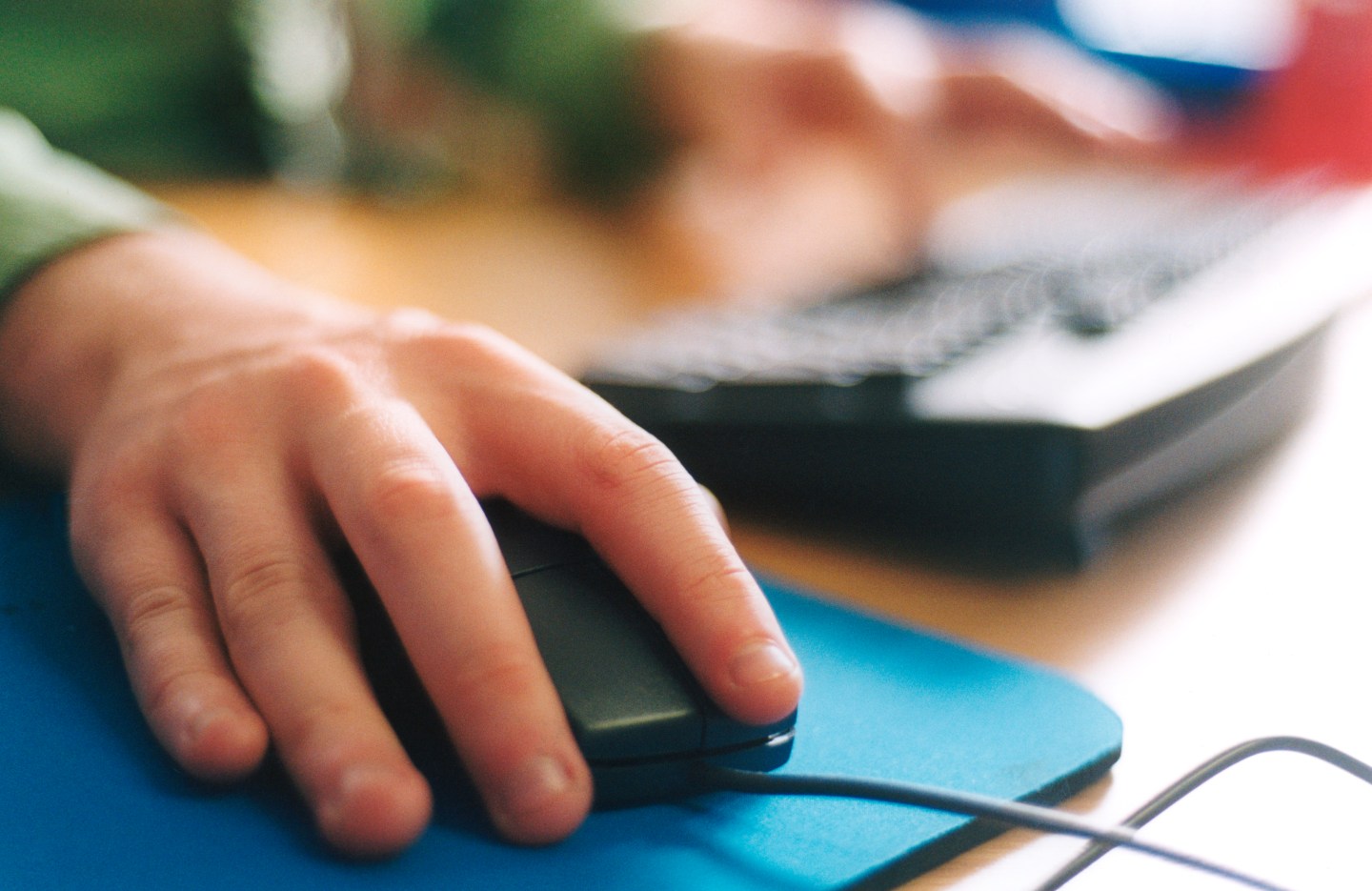 Office worker using mouse & computer at work,, UK