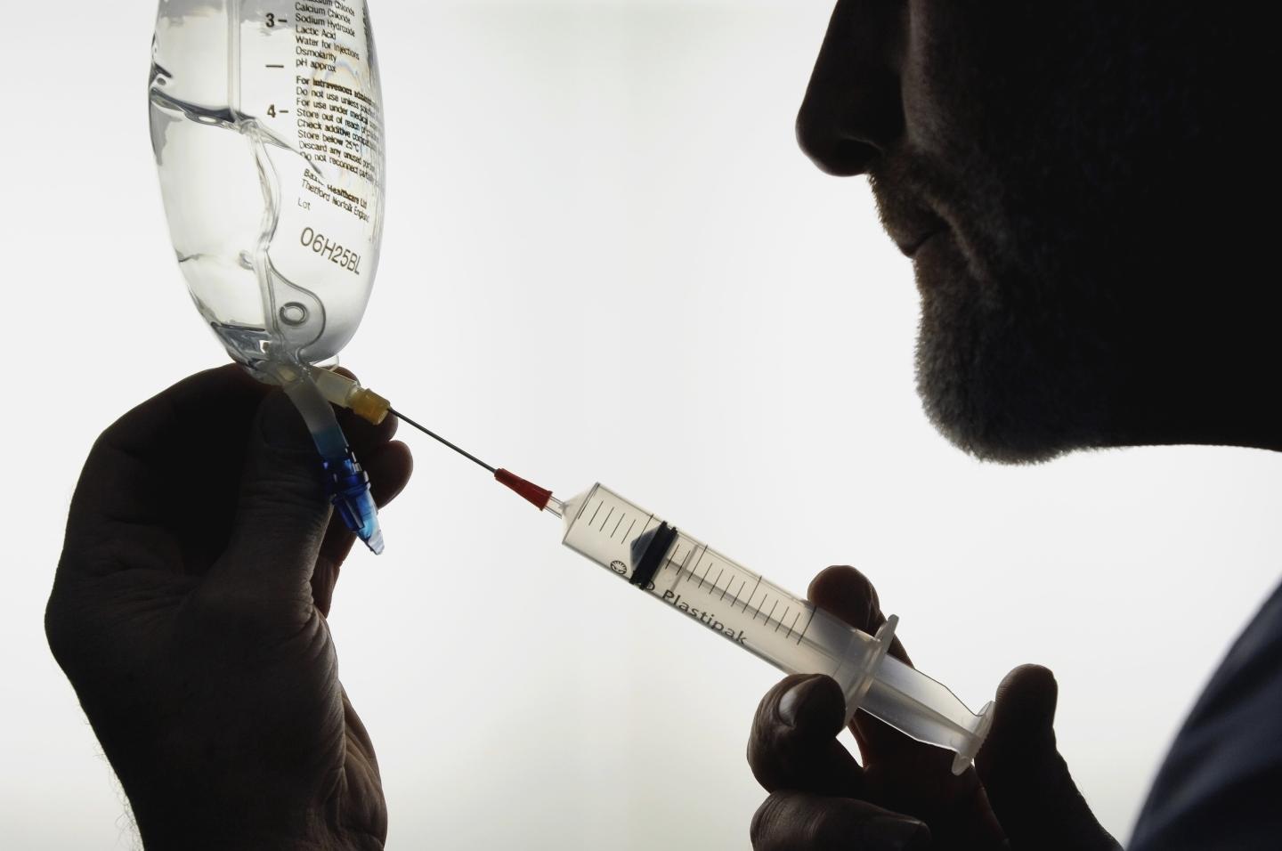Silhouette of doctor drawing sodium lactate solution into syringe