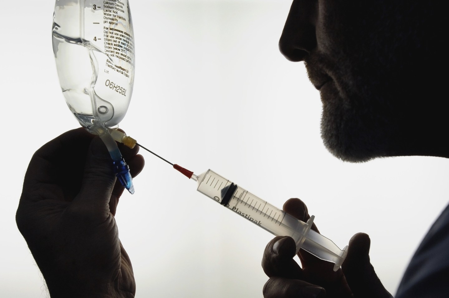 Silhouette of doctor drawing sodium lactate solution into syringe