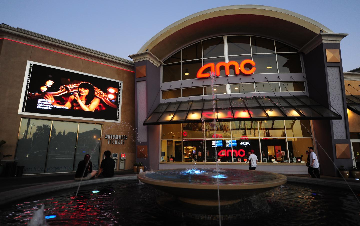 A couple watch a big screen outside movi
