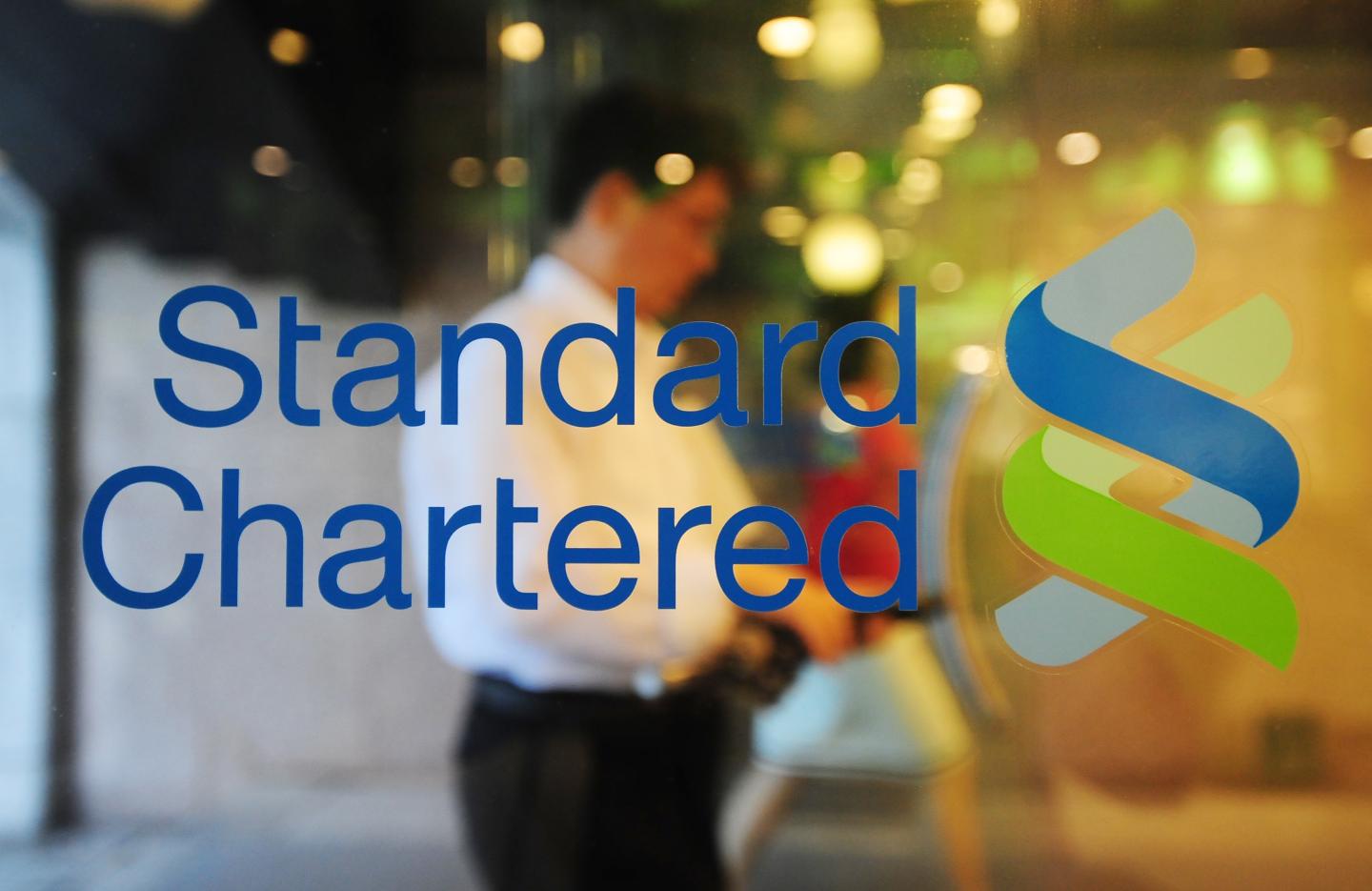 A man walks past a logo of Standard Char