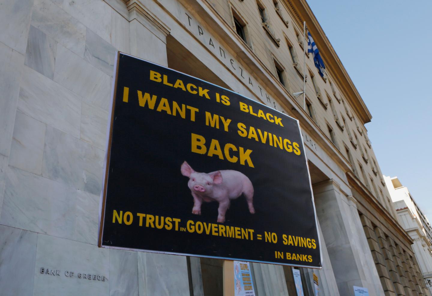A Greek bondholder holds a sign as he takes part in a protest outside the Central Bank of Greece in Athens