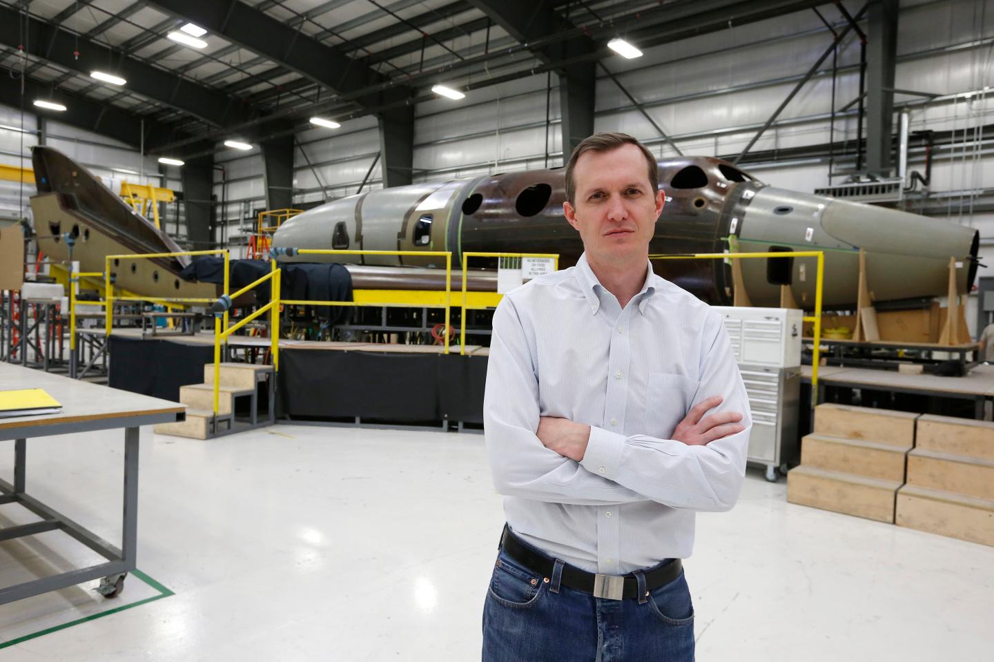 Virgin Galactic's CEO George T. Whitesides stands in front of their new spaceship N202VG, which the company began building 2 and a half years ago, in a hangar at Mojave Air and Space Port in Mojave, California