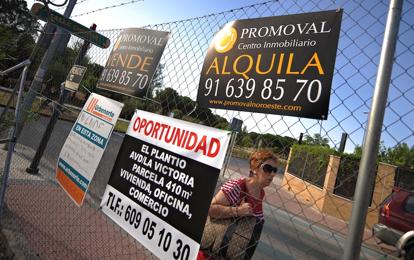 A pedestrian walks past signs which advertise properties to