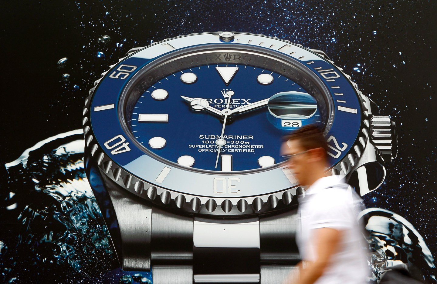A man walks past an advertising poster of Swiss watch manufacturer Rolex in Zurich