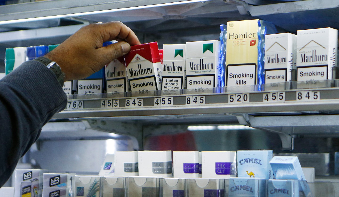 A shopkeeper reaches for a packet of cigarettes in a newsagent in London