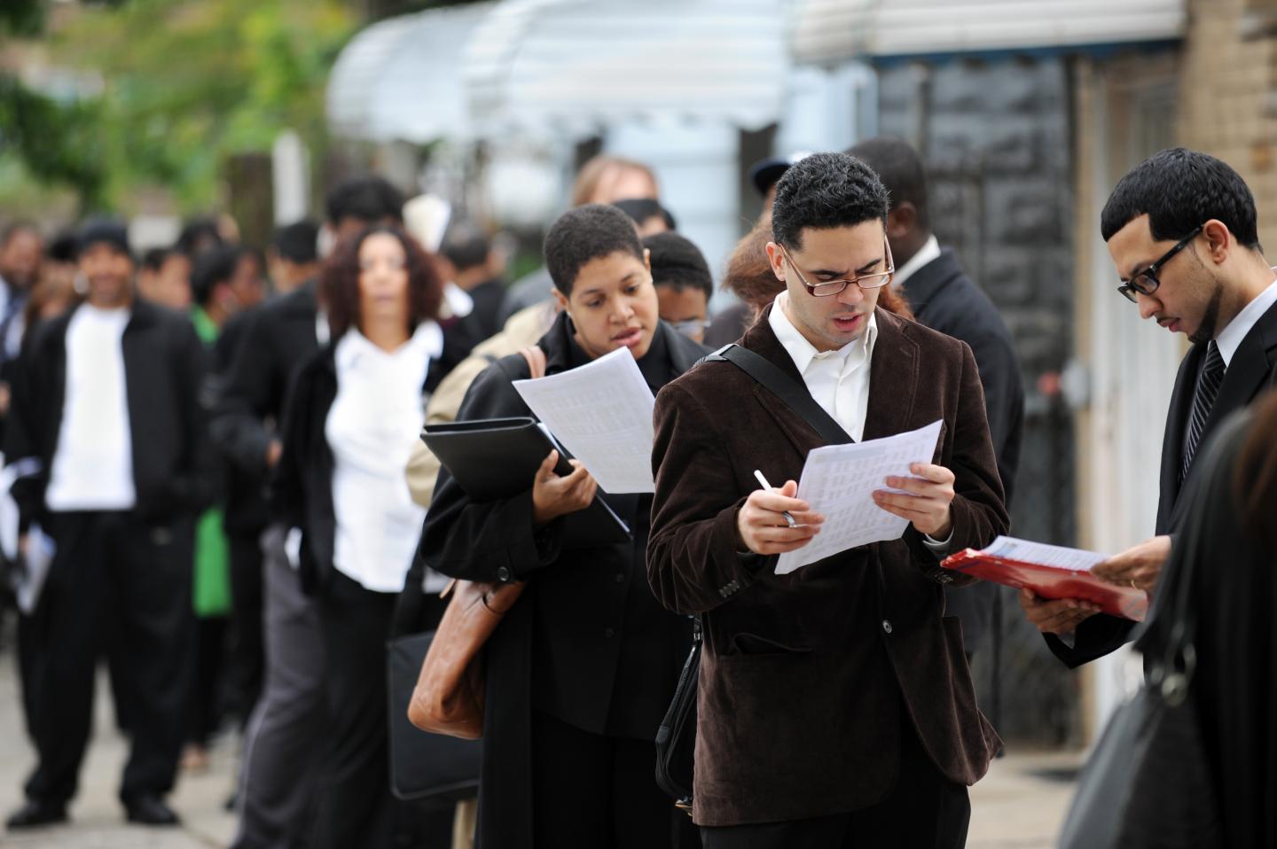 People seeking jobs wait in a line that