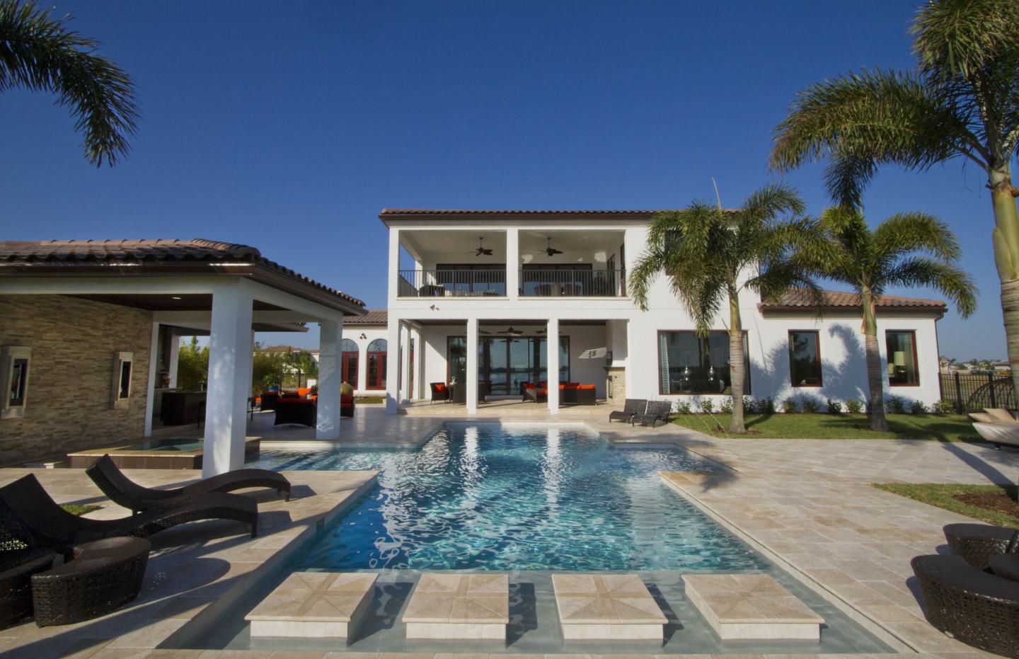 Luxury Home worth several million dollars pool with palm trees and blue sky