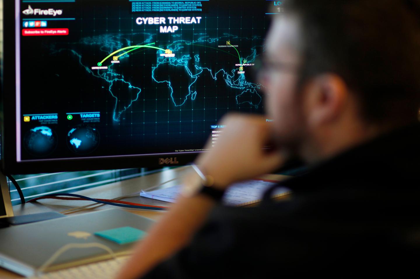 FireEye information analyst works in front of a screen showing a near real-time map tracking cyber threats at the FireEye office in Milpitas, California