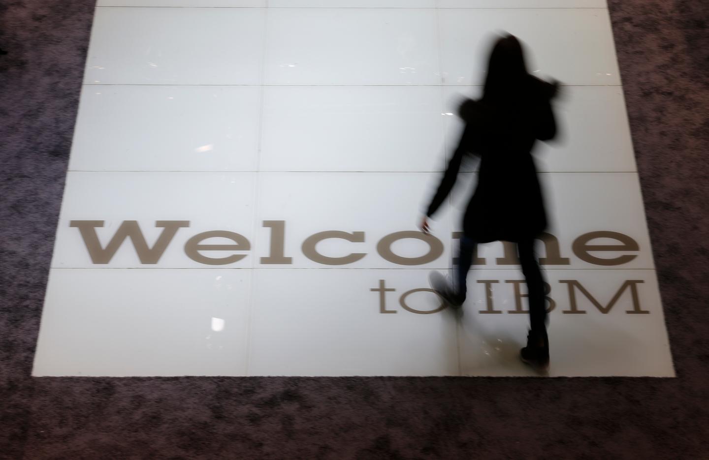 A woman walks over a welcoming sign at the booth of IBM at the CeBIT trade fair in Hanover