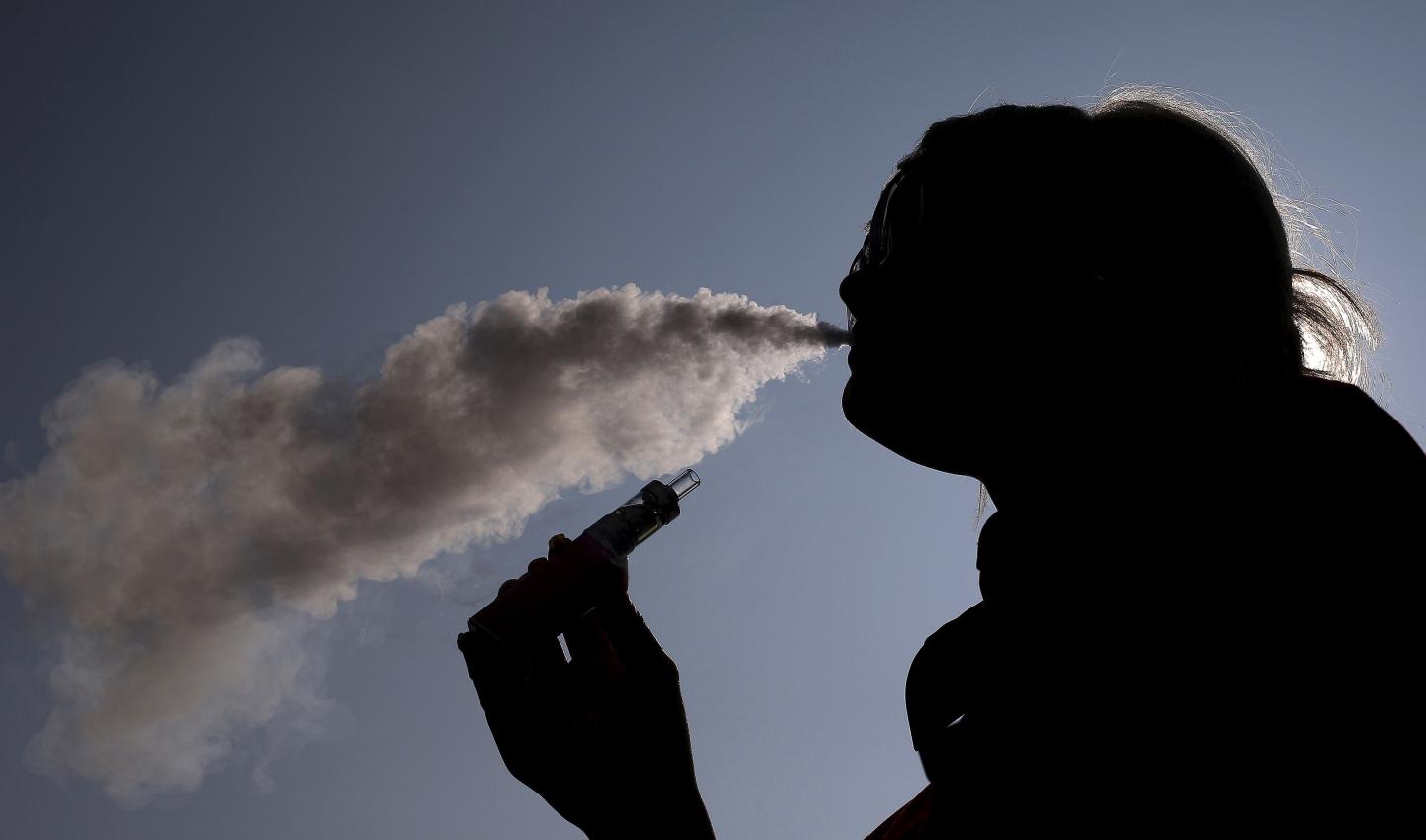 A woman exhales vapour from an e-cigarette outside the offices of British e-cigarette manufacturer Totally Wicked in Blackburn