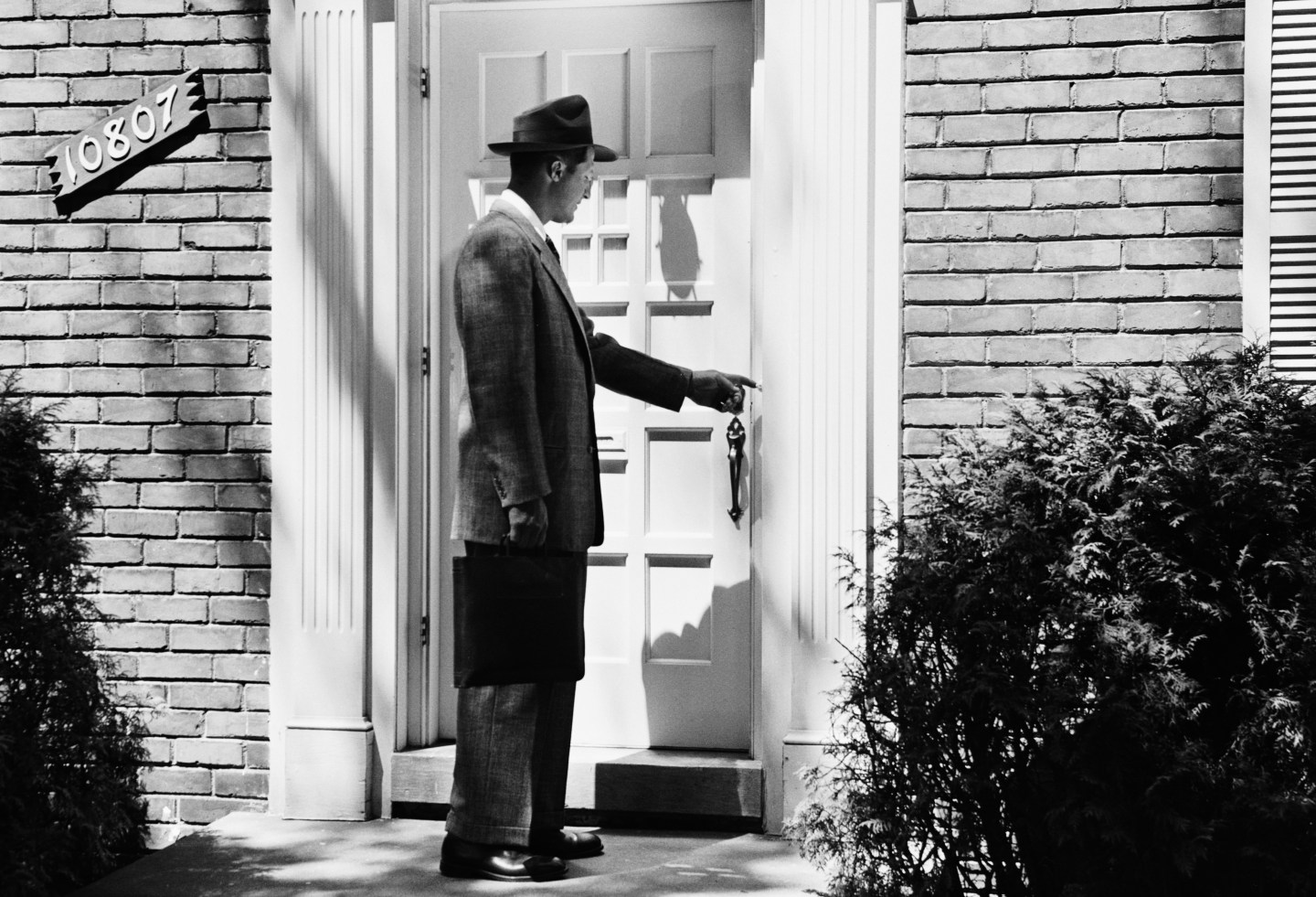 A man ringing the doorbell of a house in 1952.