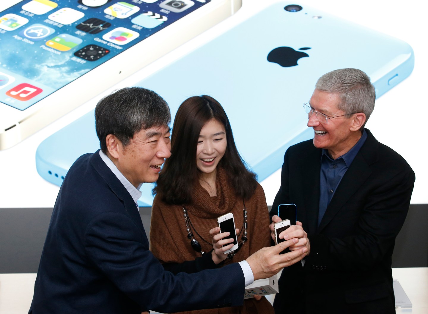 Apple Inc. CEO Tim Cook and China Mobile's Chairman Xi Guohua pose with a customer at an event celebrating the launch of Apple's iPhone on China Mobile's network in Beijing