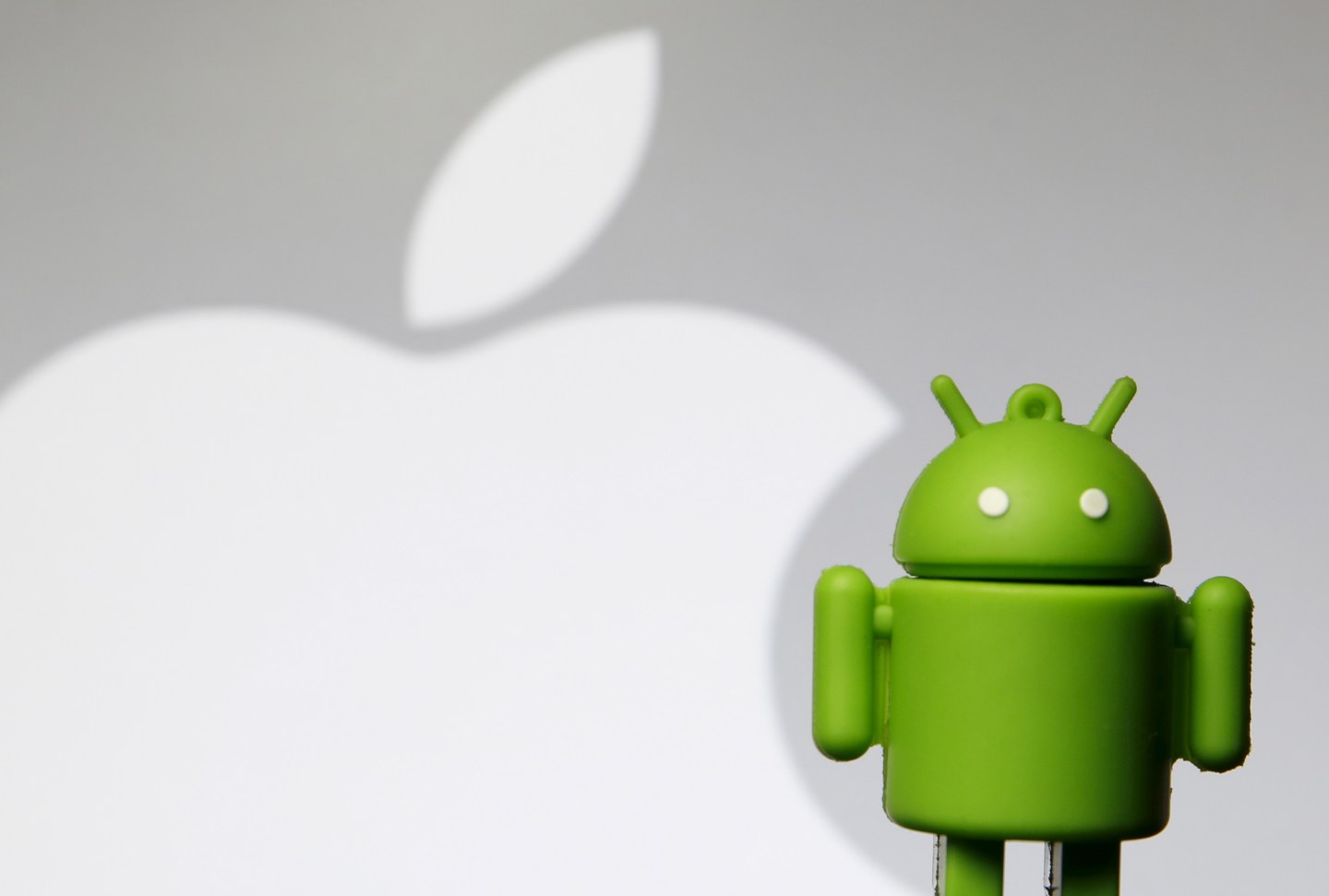 Android mascot is seen in front of a displayed logo of Apple in this photo illustration taken in Zenica
