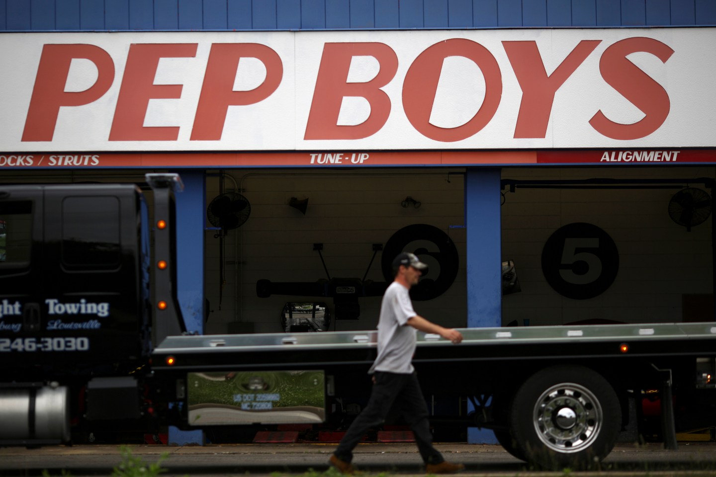 A tow truck driver walks past a Pep Boys Company auto repair and service center in Clarksville, Indiana, U.S. on Wednesday, June 3, 2015. Pep Boys earnings are scheduled to be released on June 8. Photographer : Luke Sharrett / Bloomberg