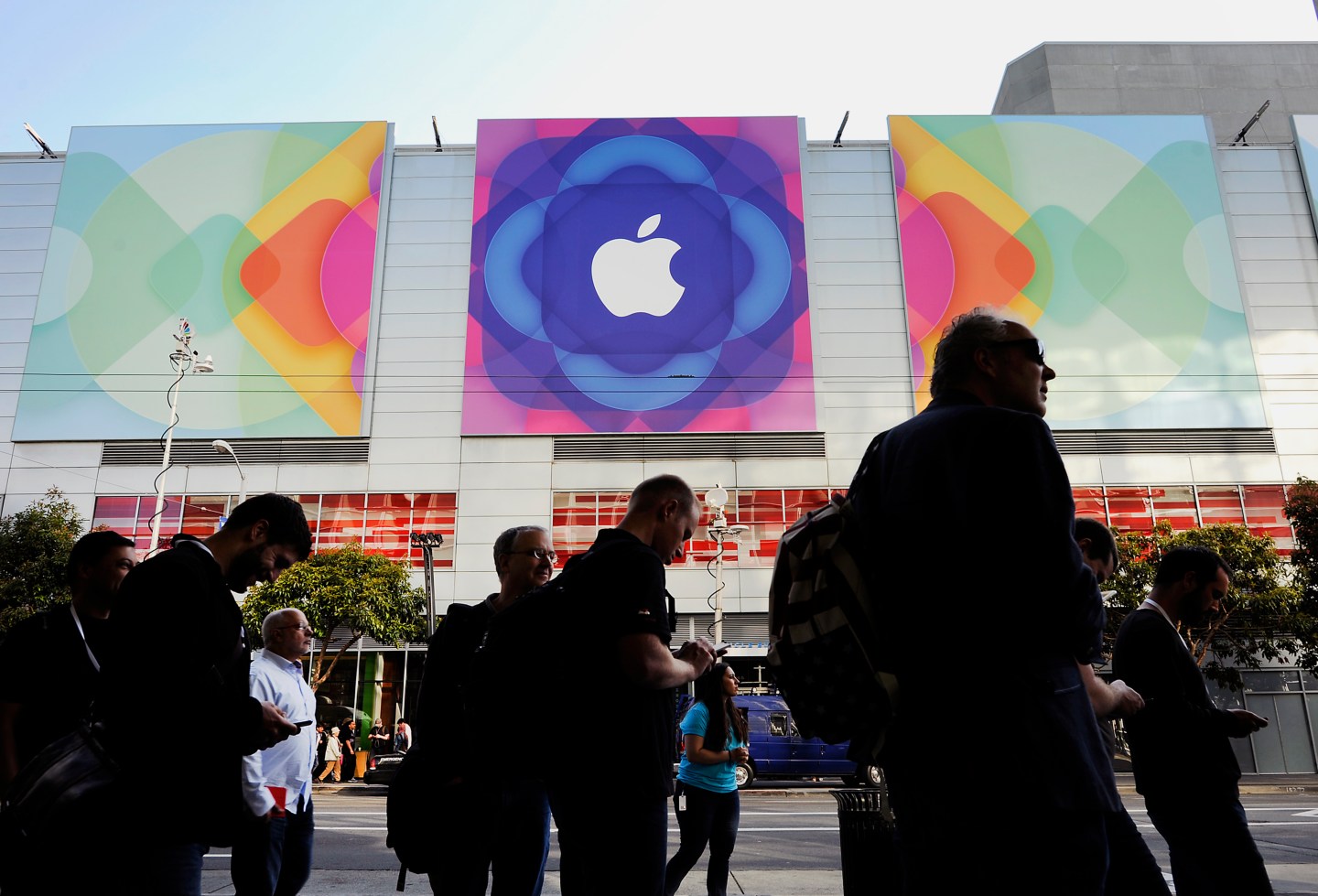 The Apple Inc. logo is displayed outside as attendees line up to enter the Moscone Center before the start of the Apple World Wide Developers Conference (WWDC) in San Francisco, California, U.S., on Monday, June 8, 2015. Apple Inc., the maker of iPhones and iPads, will introduce software improvements for its computer and mobile devices as well as reveal new updates, including the introduction of a revamped streaming music service. Photographer: Michael Short/Bloomberg via Getty Images